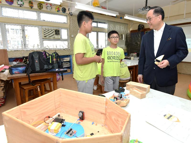 創新及科技局局長楊偉雄（右）今日（五月十七日）在浸信會天虹小學細聽學生講述如何製作小船。