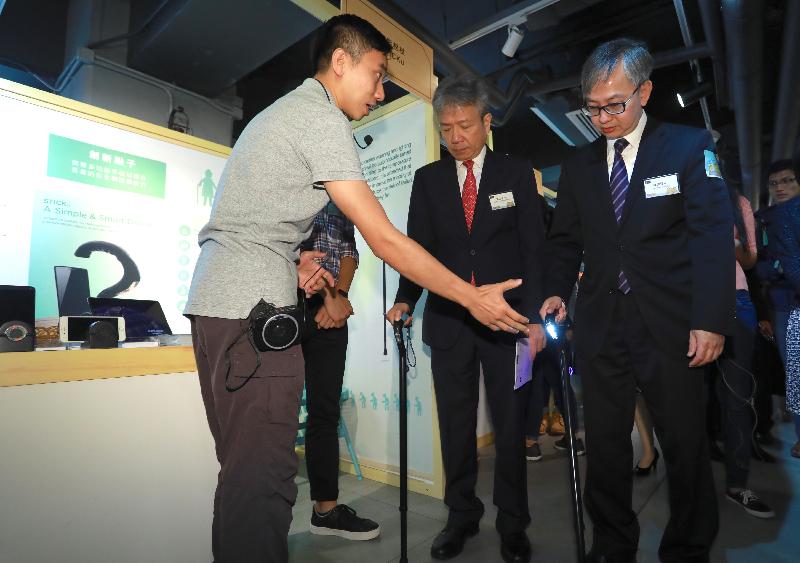 The Acting Secretary for Innovation and Technology, Dr David Chung (first right), and the Chairperson of the Social Innovation and Entrepreneurship Development Fund Task Force, Professor Stephen Cheung (centre), try out the multi-functional smart stick for the elderly at the Social Innovation Fair today (June 7).