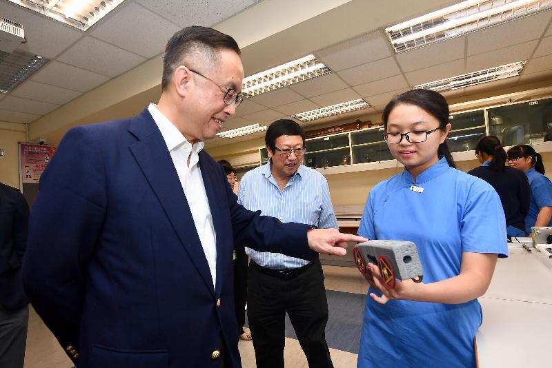 The Secretary for Innovation and Technology, Mr Nicholas W Yang (first left), chats with a student who took part in rocket car competitions during his visit to SKH Tang Shiu Kin Secondary School today (May 27).